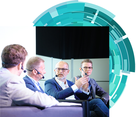 Four men engaged in conversation while seated on a stage, sharing insights with an audiences.
