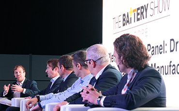 A group of speakers presenting on a stage at a show floor event